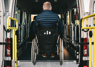 Photo d'une personne en fauteuil roulant qui entre dans un véhicule de transport adapté